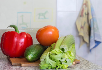 fresh peppers, tomatoes and cucumber with celery on the table