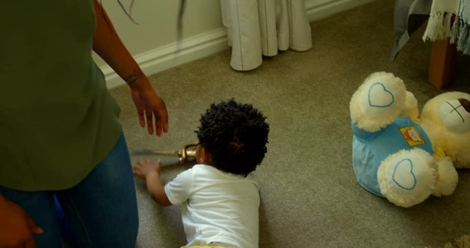 High angle view of cute little black boy playing and lying on floor of comfortable home 4k