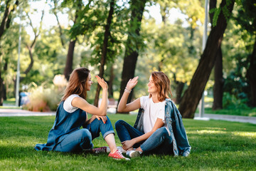 Happy female friends raising hands up giving high five in city park