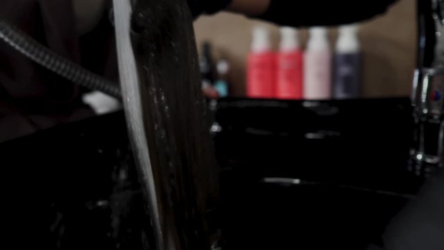 Hairdresser washes a strand of hair under the tap for hair extensions. 4K