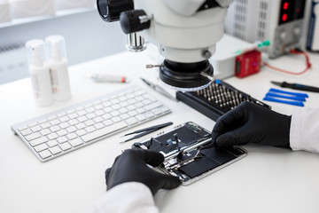 Technician repairing broken mobile phone in white office