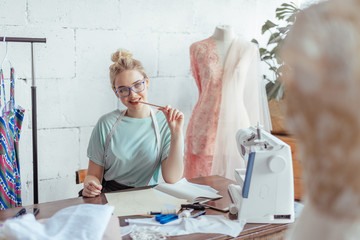 Tailor measuring Beautiful fashion designer sits at workplace drawing or writing down the results...