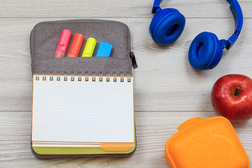 Exercise book on bag-pencil case with color felt pens and marker, yellow sandwich box, apple and...