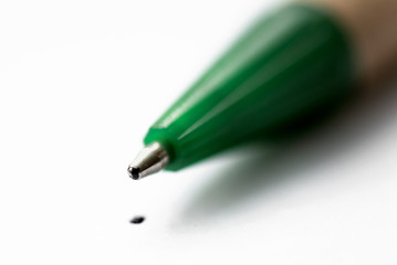 Ball pen tip and a dot on a white paper page sheet close up background.