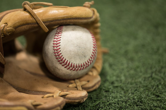 Closeup of Baseball Glove and Baseball on turf