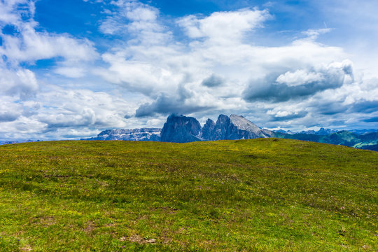 Alpe di Siusi, Seiser Alm with Sassolungo Langkofel Dolomite, a large green field with clouds in the sky