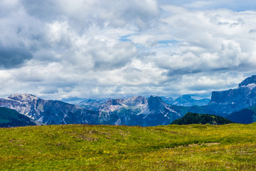 Obraz premium Alpe di Siusi, Seiser Alm with Sassolungo Langkofel Dolomite, a large green field with a mountain in the background