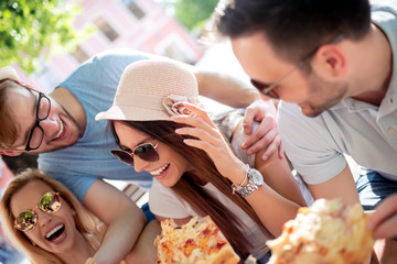 Happy group of people eating pizza outdoors