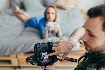 creative photographer pointing at the screen of the camera while working with a woman. close up photo. blurred background