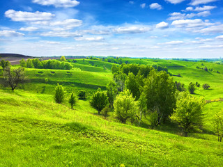 Picturesque hilly landscape with bright blue cloudy sky