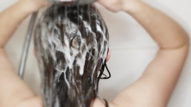 My MovieWoman washes the hair with shampoo in shower.  Young caucasian woman is washing long hair in shower cabin.