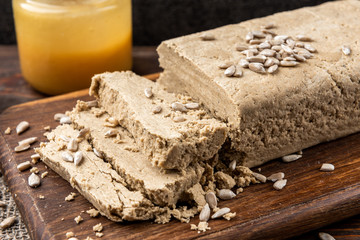 Sunflower halva and seeds on dark wooden background.