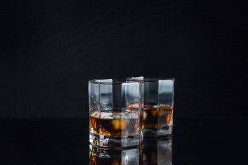 Two glasses of whiskey with ice isolated on black background..