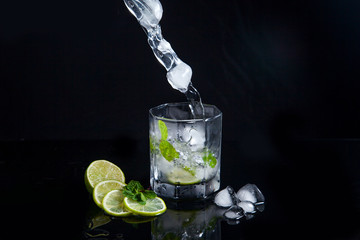 Summer cocktail mojito with splash on black background..