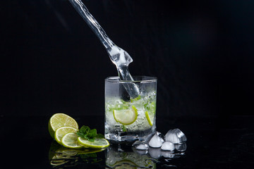 Summer cocktail mojito with splash on black background..