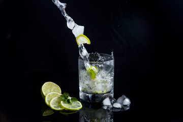 Summer cocktail mojito with splash on black background..