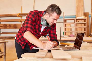 Handwerker in der Werkstatt am Laptop