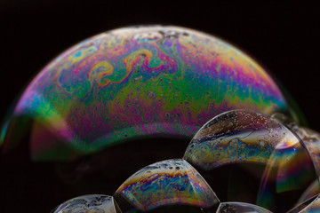 A bubble in rainbow colors on a black background.