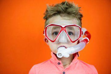 funny boy in swimming goggles and snorkel on bright orange background