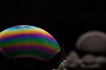A bubble in rainbow colors on a black background.