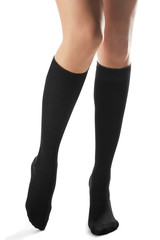 Cropped front shot of woman's slender legs wearing black knee socks. The lady is making a step against the white background. Comfortable legwear for ladies and girls. Fashionable women's hosiery.