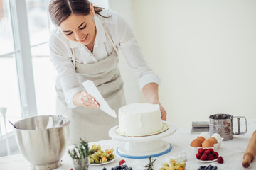 happy girl enjoys smoothing the homemade cake. close up photo