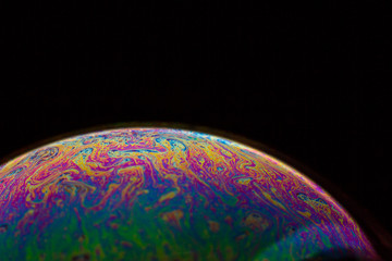 A bubble in rainbow colors on a black background.