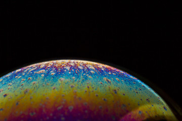 A bubble in rainbow colors on a black background.