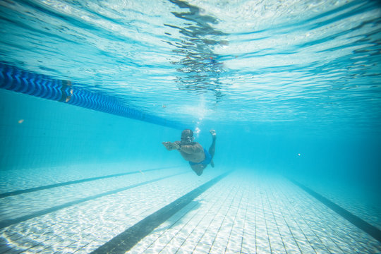 Underwater image of a male swimmer diving and swimming in a swimming pool to train