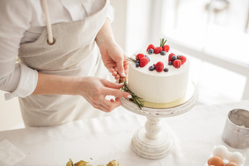 woman's hands putting greenery on the edge of cake, art, beauty concepts