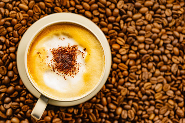 Cappuccino cup on roasted coffee beans.