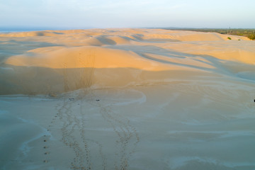 Aerial view of footprints trails in sand dunes at sunrise