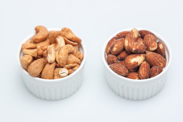 salted Cashews and almonds snack put on white background, Isolate dry and salted cashews and almonds in small white cup