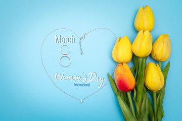 International Women's Day with flowers and heart shape necklace on blue background