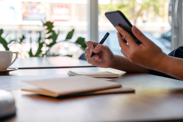 Closeup image of a woman holding and using mobile phone while working in office