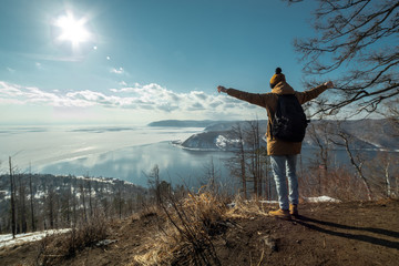 Obraz premium Traveler stands on a mountain and looks at the beautiful view of lake Baikal. Winter landscape.