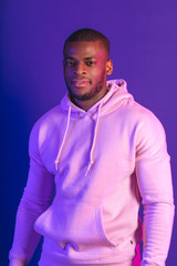 Obraz premium African male athlete looking at camera, dressed in white hoodie isolated on violet background.