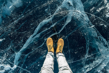 Men's yellow shoes on the pure blue ice of lake Baikal. Concept tourism and travel to famous places...