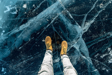 Men's yellow shoes on the pure blue ice of lake Baikal. Concept tourism and travel to famous places...