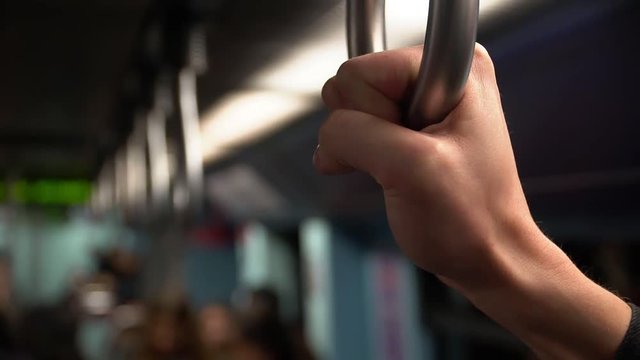A man holds on to the rail in the subway car.