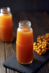 Sea buckthorn juice in a jar on a dark wooden background.