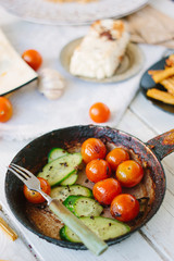 Frying pan with roasted cherry tomatoes and cucumbers.