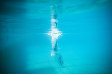 Underwater image of a male swimmer diving and swimming in a swimming pool to train