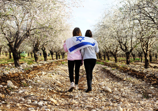 Two teenage girls are holding an Israeli flag outdoors