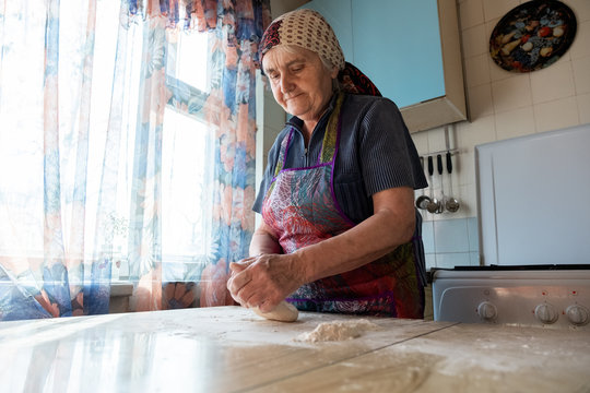 Senior woman kneading the dough in her home kitchen, grandmother cooking bakery products, fresh bread, tasty pie