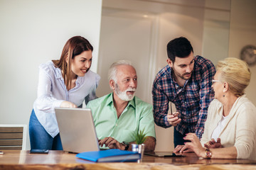 Young volunteers help senior people on the computer. Young people giving senior people introduction to internet