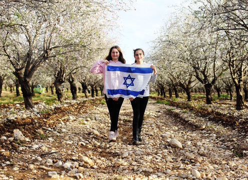 Two teenage girls are holding an Israeli flag outdoors