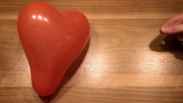 Symbol of broken heart no love, by puncture a balloon in slow motion