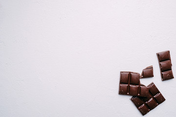 broken chocolate bar on white backdrop. confectionery design. sweets background