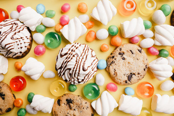 lollipop candy background, confectionery design concept. chocolate cookies, marshmallows, caramel candies on yellow table. sweet food, sugar, dessert backdrop